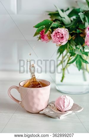 Spray Drops Splash In A Pink Cup Of Tea. Sunny Morning With Peonies Flowers On A Background. Beautif