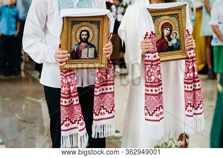 The Bride And Groom Hold In Hands Wedding Icons After The Wedding Ceremony And Leave The Church. Hap