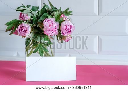Bouquet Of Pink Peonies In Glass Vase Against White Background And Wooden Table. Mothers Day Card. B