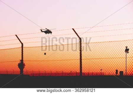 Niederstetten, Germany, April 2020. Silhouette Of Flying Helicopter With Bambi Or Monsoon Bucket Beh