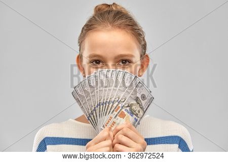 people concept - smiling teenage girl in pullover holding hundreds of dollar money banknotes over grey background