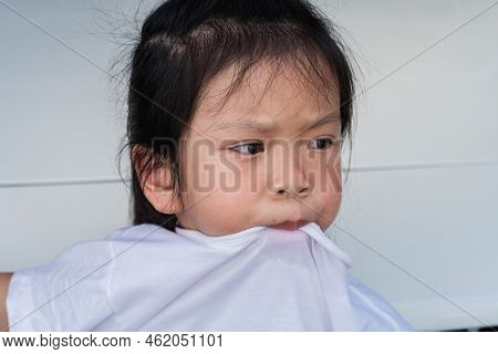 Portrait Cute Girl Pulls Her Mouth Over Collar Of Her T Shirt. Expressing Turbulent Or Embarrassed E