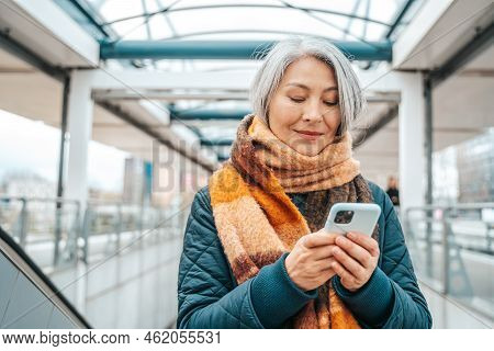 Senior Woman Send Message With A Mobile Phone In A Stransport Station