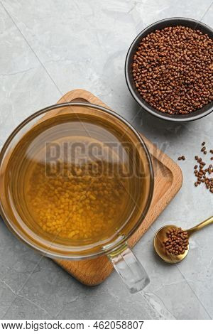 Cup Of Aromatic Buckwheat Tea And Granules On Light Marble Table, Flat Lay