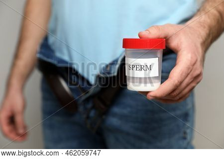 Donor With Unzipped Pants Holding Container Of Sperm, Closeup