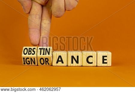 Obstinance Or Ignorance Symbol. Businessman Turns Cubes, Changes The Word Ignorance To Obstinance. B