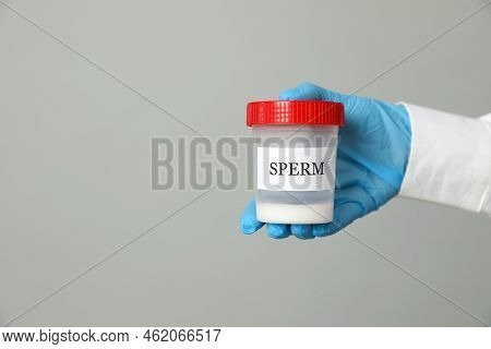 Scientist Holding Container With Sperm On Grey Background, Closeup. Space For Text