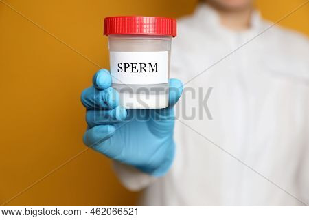 Scientist Holding Container With Sperm On Yellow Background, Closeup