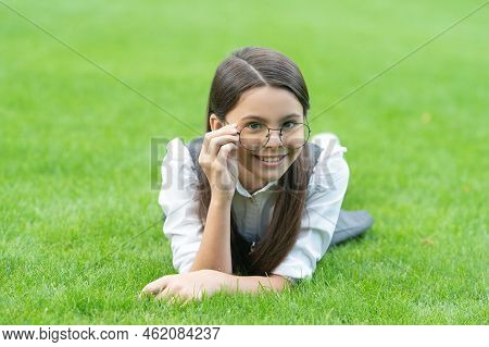 Portrait Of Happy Teener Girl Adjusting Glasses Lying On Grass After School, Girl. Teen Girl