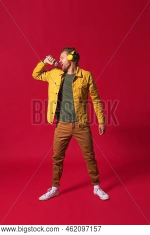 Singing Young Man Enjoying His Favorite Song Holding Microphone And Wireless Headphones Wearing Casu