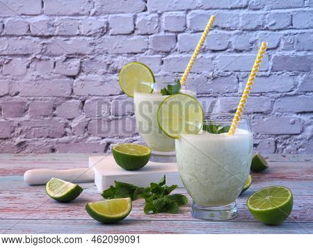 Brazilian Lemonade In Two Glasses Decorated With Lime Slices And Mint. Refreshing Milk Drink.