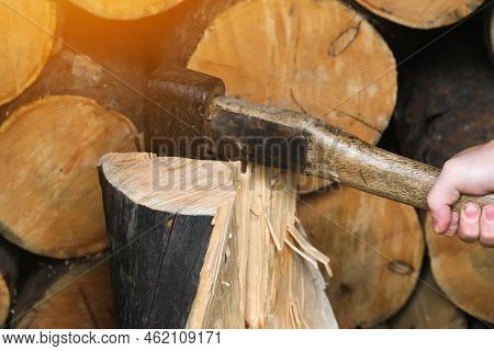 A Man Is Chopping Logs With An Axe On Chopping Block. Harvesting Of Firewood Stocks For Heating. An 