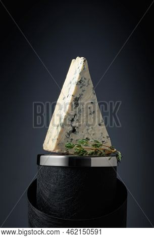 Triangle Piece Of Blue Cheese With Thyme On A Black Background.