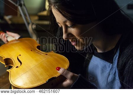 Young Woman Apprentice Violinmaker Checking Her Violin