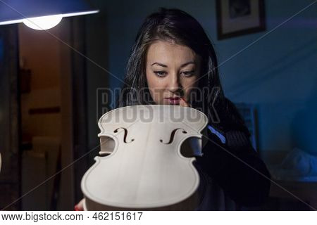 Young Woman Apprentice Violinmaker Checking Her Violin