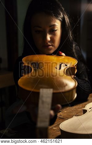 Young Woman Apprentice Violinmaker Checking Her Violin