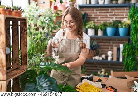 Young blonde woman florist using water difusser at florist