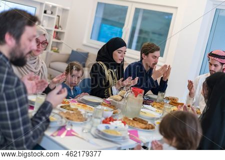 Muslim family making iftar dua to break fasting during Ramadan.