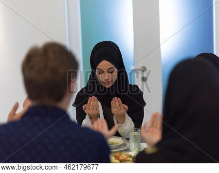 Muslim family making iftar dua to break fasting during Ramadan.