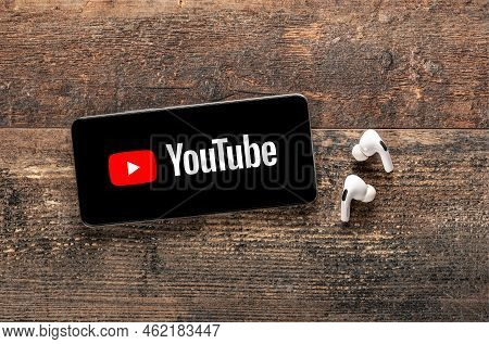 Usa, New York September 22, 2022: Close Up Of Phone With Youtube New Logo And Modern Earphones On Ol