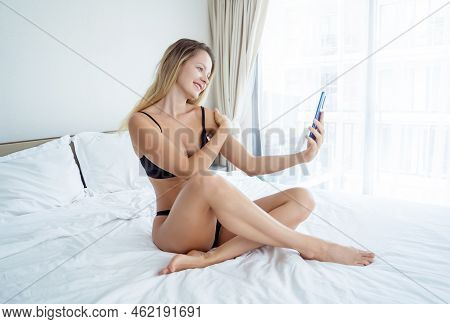 Young Sexy Woman Posing In Front Of Smartphone In His Hand And Working As Webcam Model