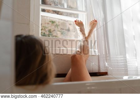 A Beautiful Mature Woman Massages Her Legs In A Bath With Candles In A Cozy And Comfortable Atmosphe