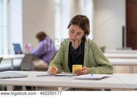 Concentrated Middle-aged Scandinavian Female Student Using Smartphone For Exam Preparation While Sit