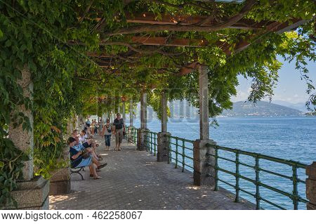 Arona, Italy - August 18, 2018: Arona Lakeside Promenade With Strolling Tourists. Arona Is A Town In