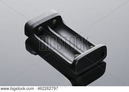Charger For Finger Batteries Close-up, Black On A Dark Background