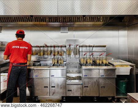 Paris, France - Sep 21, 2022: Worker At The French Fries Cooking In Multiple Deep Fryer Mat Machines