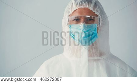 Portrait Of Immunologist In Ppe Suit And Goggles With Medical Mask Looking At Camera Isolated On Gre