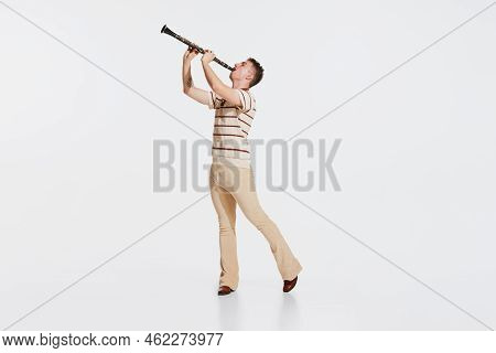 Young Man Wearing 50s, 60s Fashion Style Clothes Playing Clarinet On White Studio Backround. Music, 