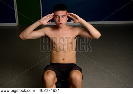 Shirtless 19 Year Old Teenage Boy Soing Situps On An Exercise Bench
