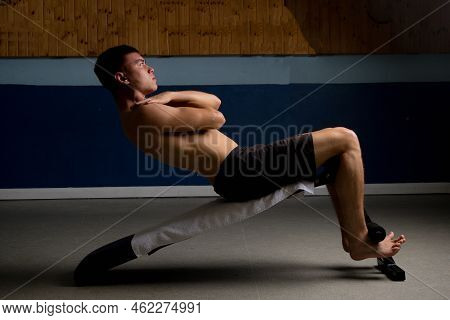 Shirtless 19 Year Old Teenage Boy Soing Situps On An Exercise Bench