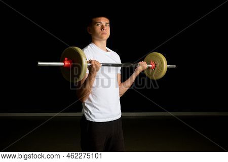 19 Year Old Teenage Boy Excercising His Biceps With A Barbell
