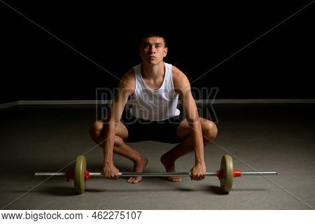 19 Year Old Teenage Boy In A Tanktop Lifting A Barbell