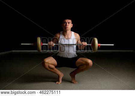 19 Year Old Teenage Boy In A Tanktop Lifting A Barbell