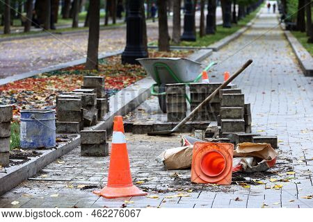 Road Works, Street Repairs And Tiles Lying. Orange Roadblock Cones, Tools And Stone Blocks On Sidewa