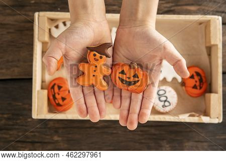 Childrens Hands Hold Gingerbread In Form Of Pumpkin And Gingerbread Man. Festive Cookies For Hallowe