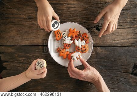 Hands Reach For Handmade Eatable Gingerbread On Plate. Top View. Halloween Pumpkin, Ghosts And Ginge