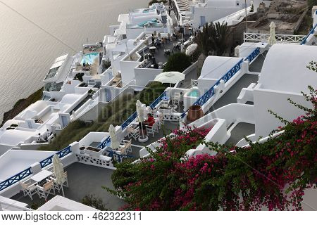 Imerovigli, Santorini, Greece - July 1, 2021: Whitewashed Houses With Terraces And Pools And A Beaut