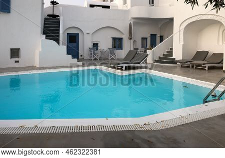 Imerovigli, Santorini, Greece - July 1, 2021: Whitewashed Houses With Terraces And Pools And A Beaut