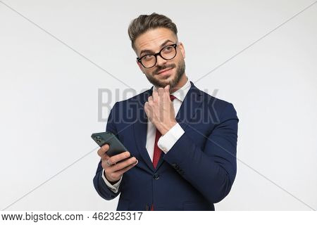 happyman smiling and dreaming while holding phone and texting in front of white background in studio