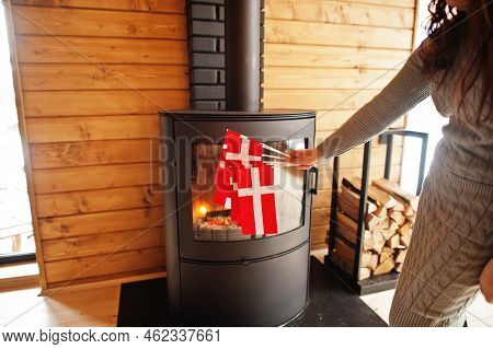 Woman Hold Denmark Flags Against Fireplace. Travel To Scandinavian Countries. Happiest Danish People