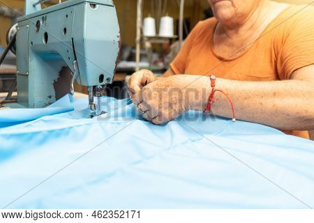 Elderly Woman Sewing A Guayabera Shirt On A Sewing Machine