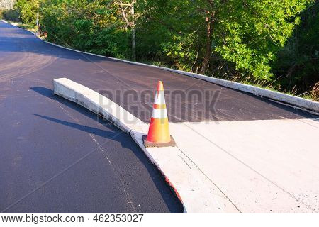 Orange Road Construction Safety Traffic Cone On Fresh Black Asphalt Surface During Road Repair Const