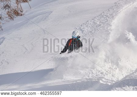 VALMOREL, FRANCE - CIRCA, 2019: Snowboarder in deep snow free ride coming down the slope after heavy snowfall in Valmore, French Alps