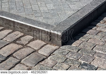 Corner Of A Pedestrian Sidewalk Made Of Stone Rectangular Brick Tiles And Granite Curb Dirty In Mud 