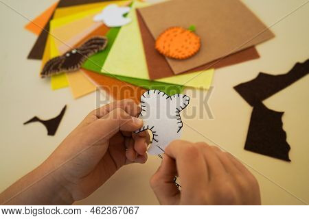 Close-up Of The Hands Of A Child Who Makesdecorative Garland For Halloween From Felt Greetings And F