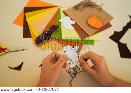 Close-up Of The Hands Of A Child Who Makesdecorative Garland For Halloween From Felt Greetings And F